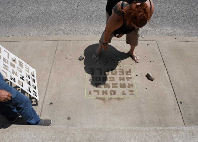 A woman paints on the sidewalk in hindman, kentucky, as part of a program for those in addiction recovery in eastern kentucky.