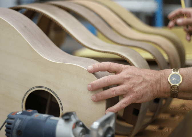 A hand touches some of the guitars being built at troublesome creek stringed instrument company, based in appalachian kentucky.