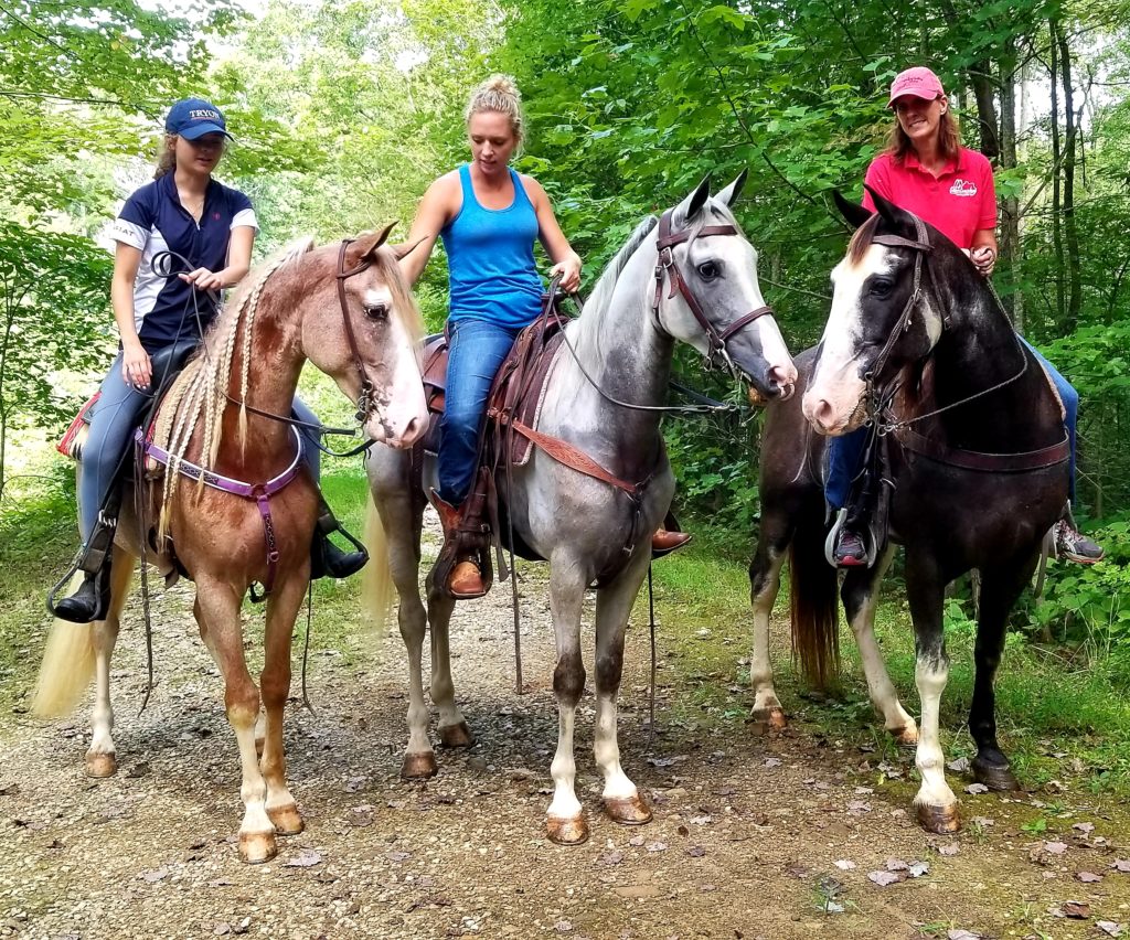 Three women on horseback in eastern kentucky. They are riding smokey valley horses part of a breed project by morehead state.
