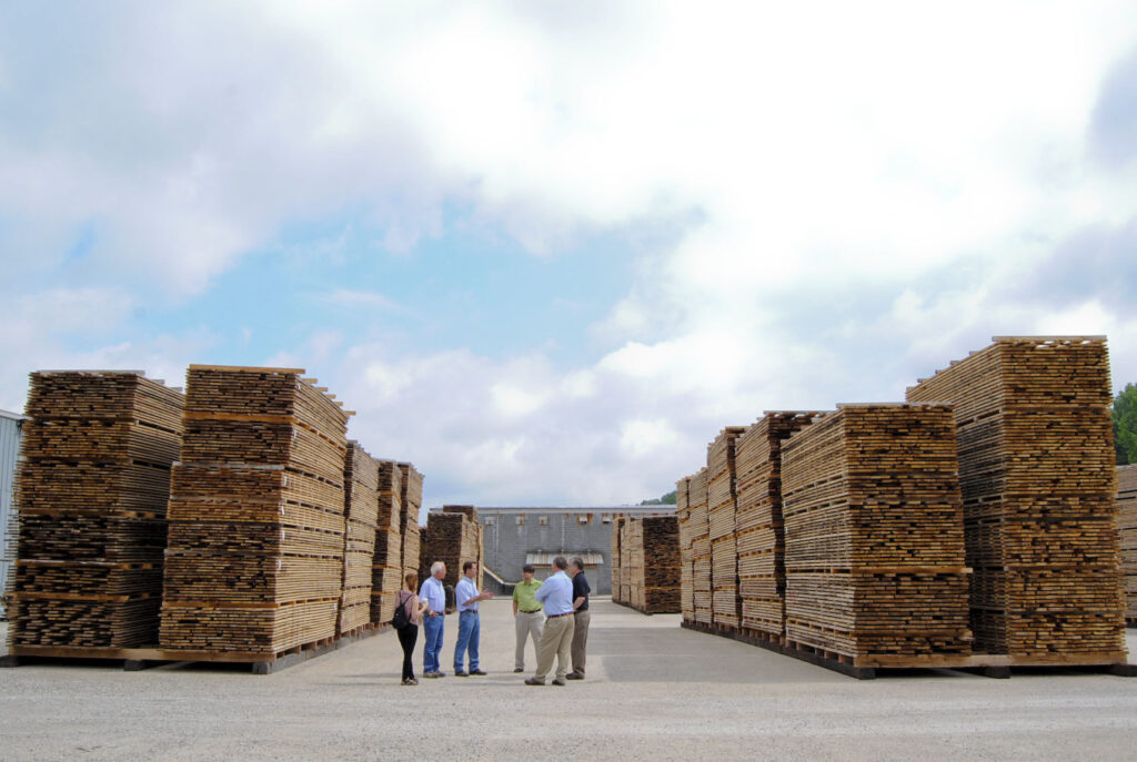 A group of people stand outside in front of several stacks of lumber at powell valley millwork.