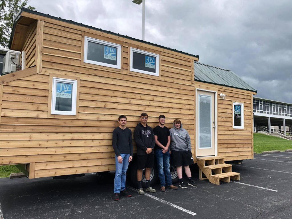 Four students stand with a tiny house produced in Eastern Kentucky as part of vocational training and program by KVEC.