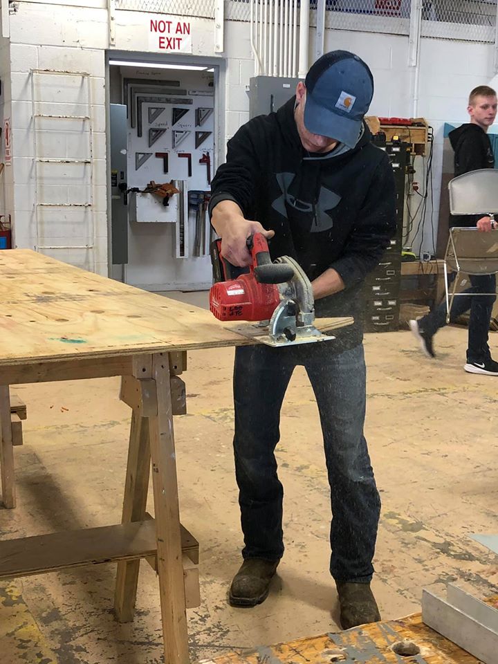 A student sands a piece of wood while making a tiny house at vocational school in Eastern Kentucky.