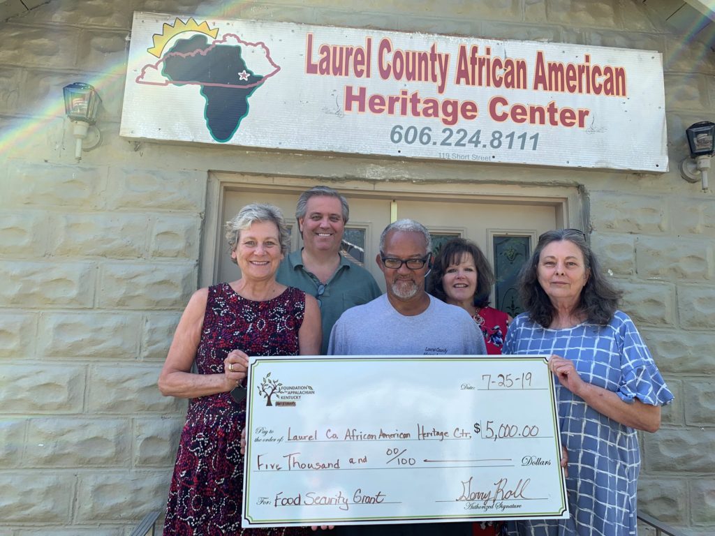 A group stands with a big check in front of Laurel County African American heritage center in eastern kentucky.