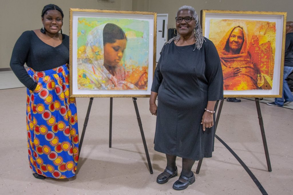 Two women pose with Winchester Kentucky portraits as part of the I was here exhibit, racial equity work by clark county residents