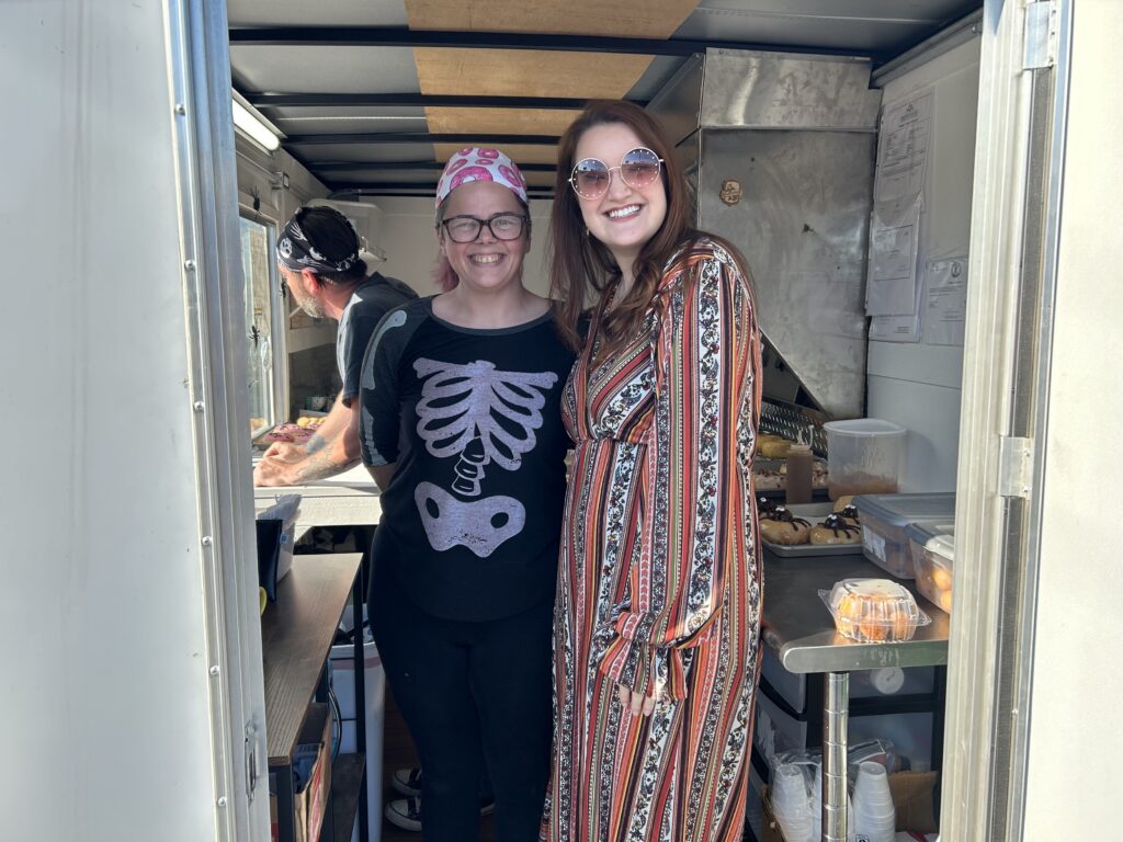 Alex stands to the right of one of our clients inside a food truck