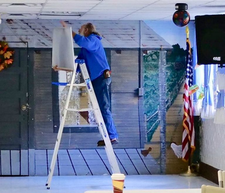 John stands on a ladder while completing an energy efficiency upgrade at Hemphill Community Center in Eastern Kentucky.
