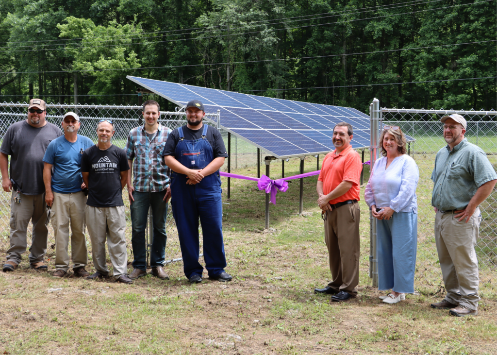 SEveral people stand in front of solar panels at buckhorn nonprofit.