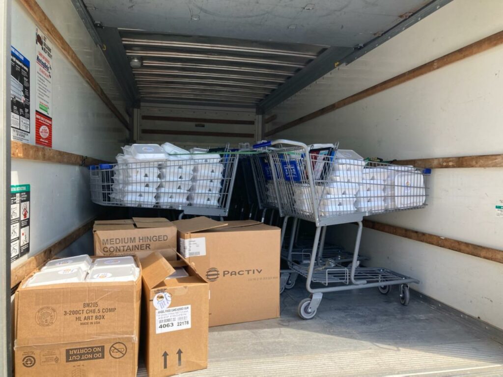 Shopping carts and boxes are inside of a Uhaul loaded with boxed meals.