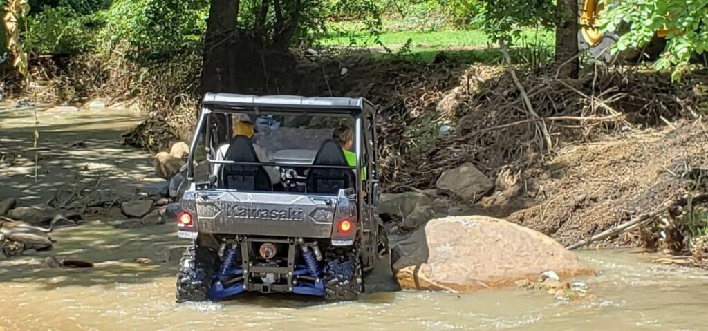 An off road vehicle drives through a creek to deliver food in Eastern Kentucky.
