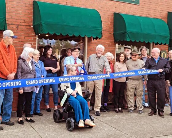 A group of people stand behind a ribbon at the grand re-opening of Top Drawer