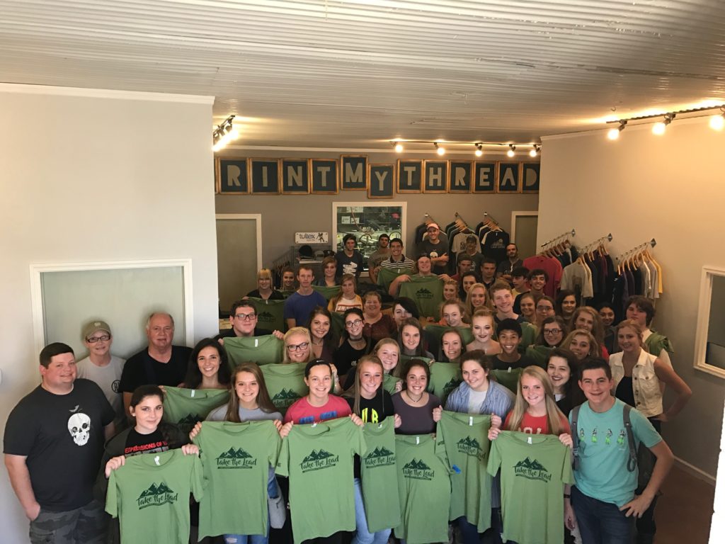 High school students stand with their tshirts inside Print My Threads. The leadership program recently toured the Eastern Kentucky facility