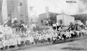 an old picture showing a crowd of children stand on main street