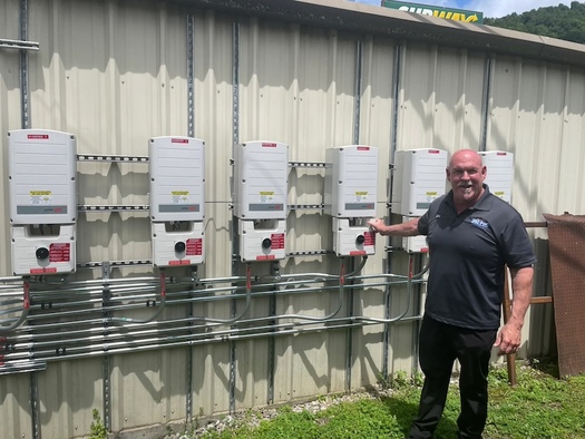 Mike Long with his battery and solar inverter mounted on side of his store