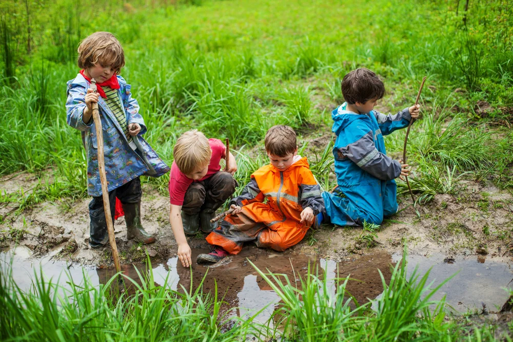 Four students in Red oaks Forest school play in a creek