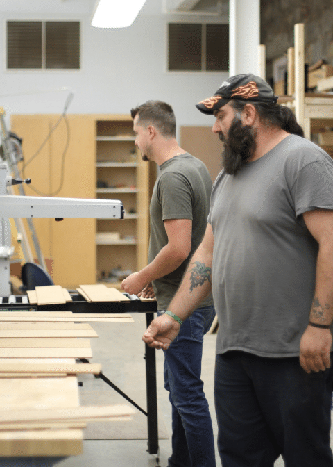 Nathan Smith, an apprentice luthier, works with Kris Patrick on a piece of wood. Smith is a former coal miner in addiction recovery