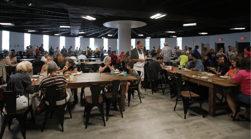 Crowds gather around tables at CANE Kitchen in Whitesburg, kentucky. The community dinners are offered for free in letcher county