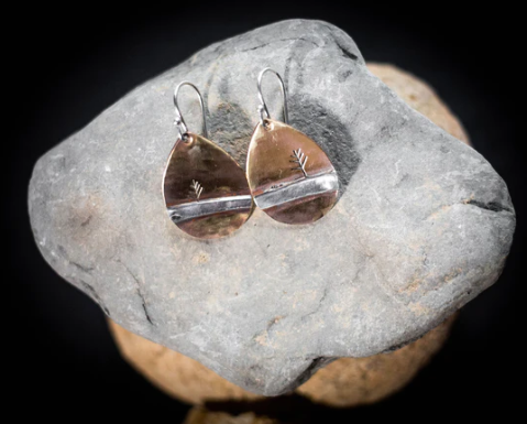 a pair of earrings created by Appalachia's daughter resting on a rock