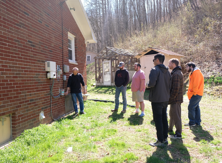 A group of students stand by a farmhouse with their instructors on a farm in floyd county.
