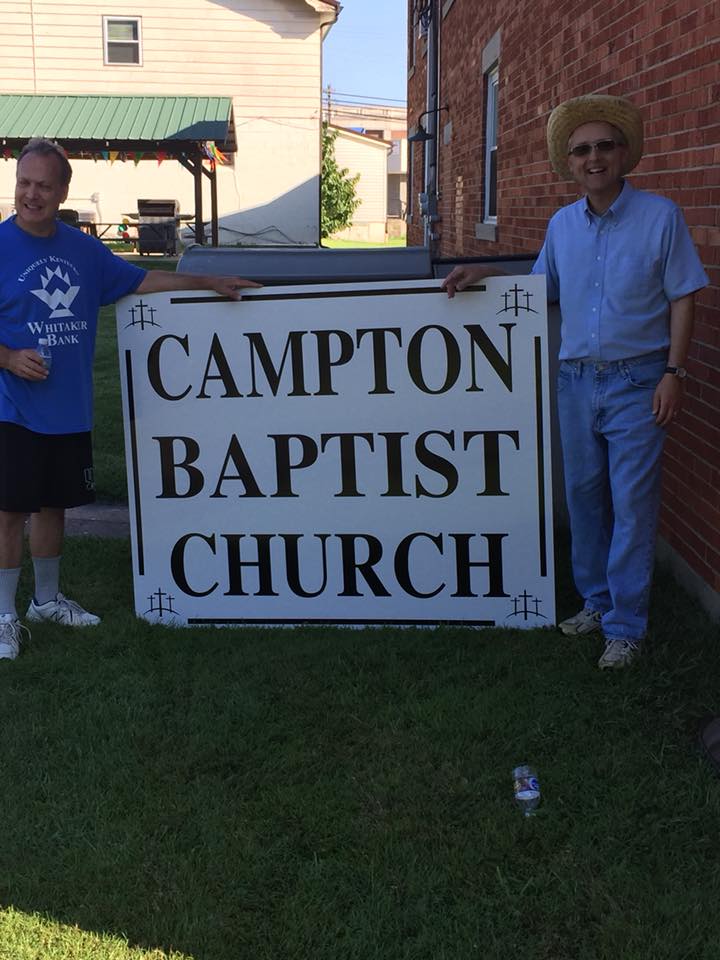 Two members of Campton Baptist Church in Wolfe County, Kentucky standard with their new sign. The EKY church added solar panels