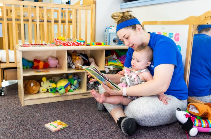 childcare provider holds and reads to a baby at new beginnings in hazard, kentucky.