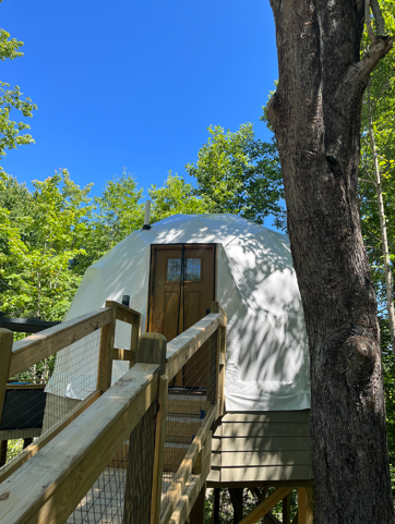 The dome with steps up to the door are pictured against a blue sky and trees.