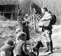 A Frontier nurse talks to patients in Eastern Kentucky. There are four kids and a caretaker pictured along with the nurse and her horse