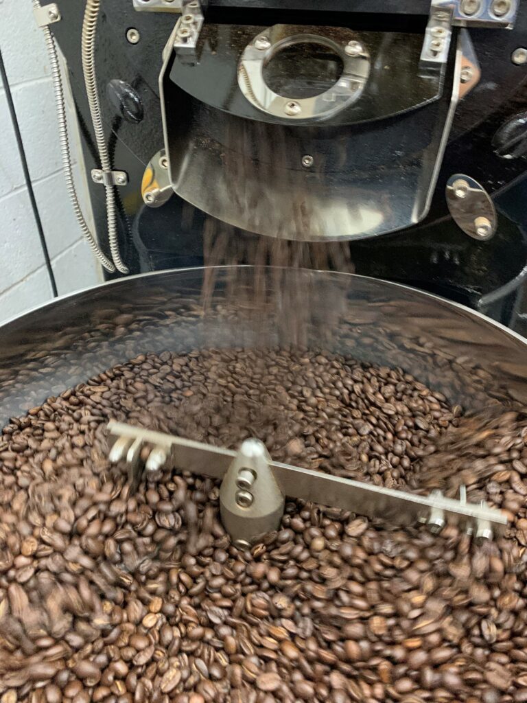 Coffee beans fall into a large roaster at goose bridle coffee in eastern kentucky.