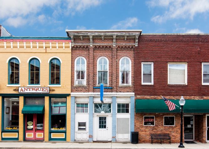 Three buildings on main street in Eastern Kentucky. Open sign hands in a door. MACED is offering economic recovery loans for COVID-19.