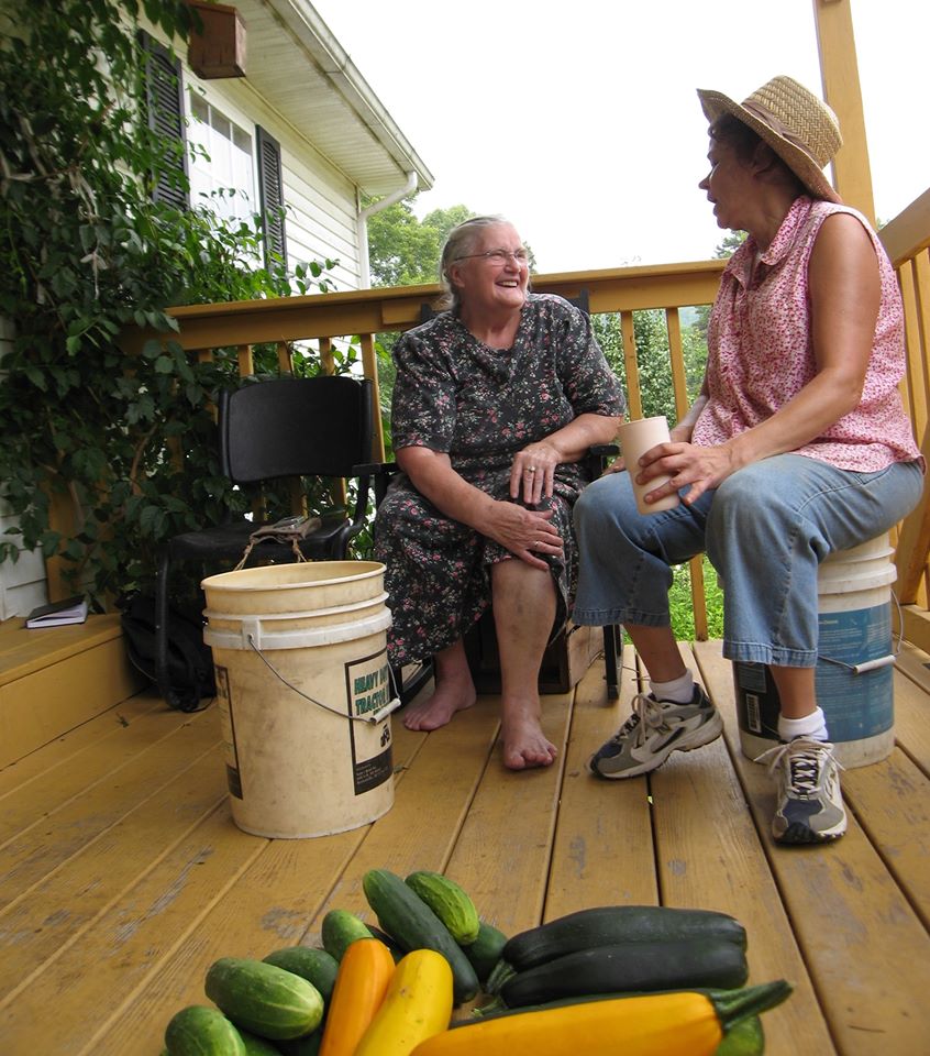 Two women talk on a porch about the Grow Appalachia program that helps Eastern Kentucky families garden and grow food 