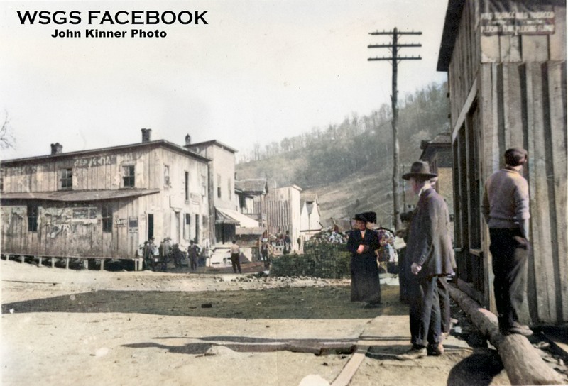 an old picture of main street with wooden buildings and people in hats