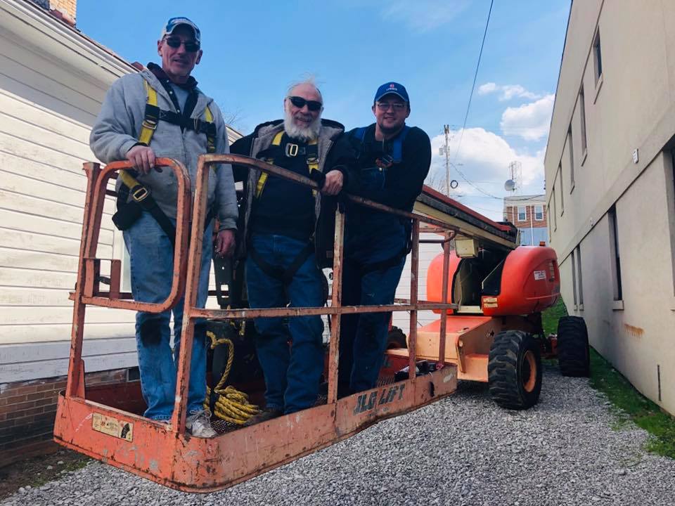 Three men on a cherry picker prepare for a solar installation in Letcher County, Kentucky.