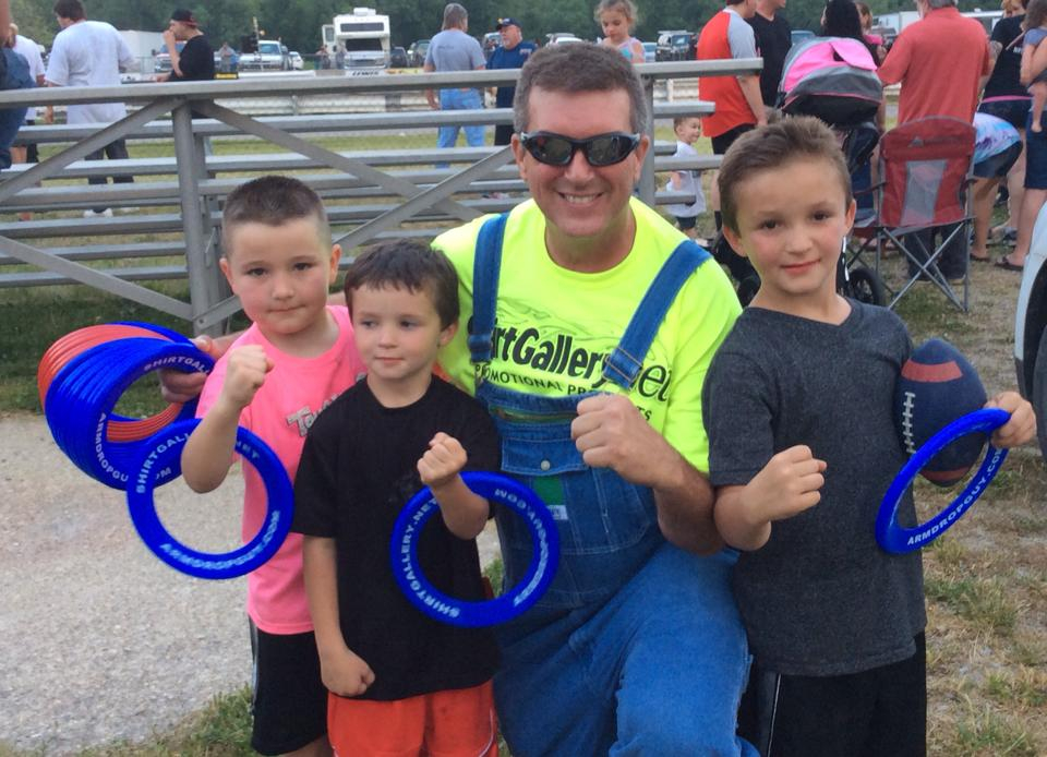 Kent Rose with three kids at a car racing event in Eastern Kentucky. His legacy continues with scholarships and other kids programming.