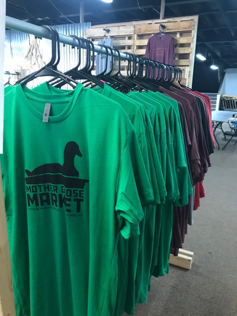 A row of tshirts for sale at appalachian Apparel on Main Street in hazard. One shift depicts the iconic Mother Goose building.