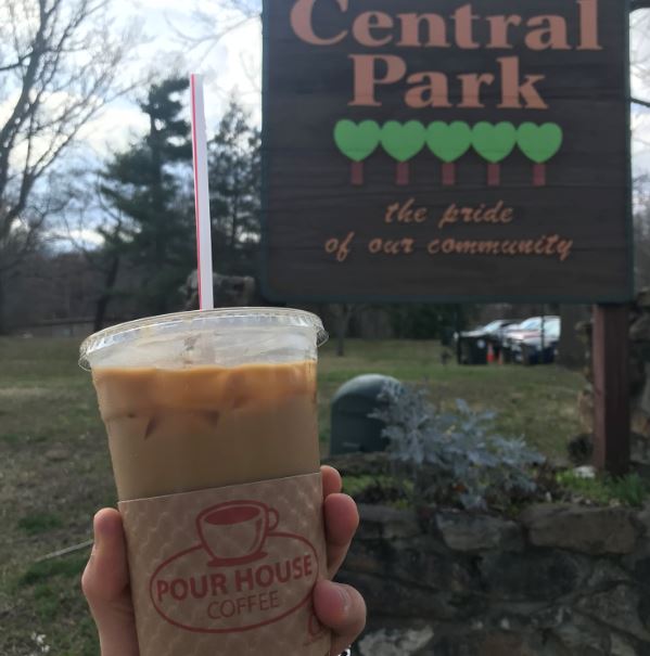 Person holds a cold brew coffee from Pour house coffee in Ashland, Kentucky, adjacent to Ashland's beautiful Central Park.