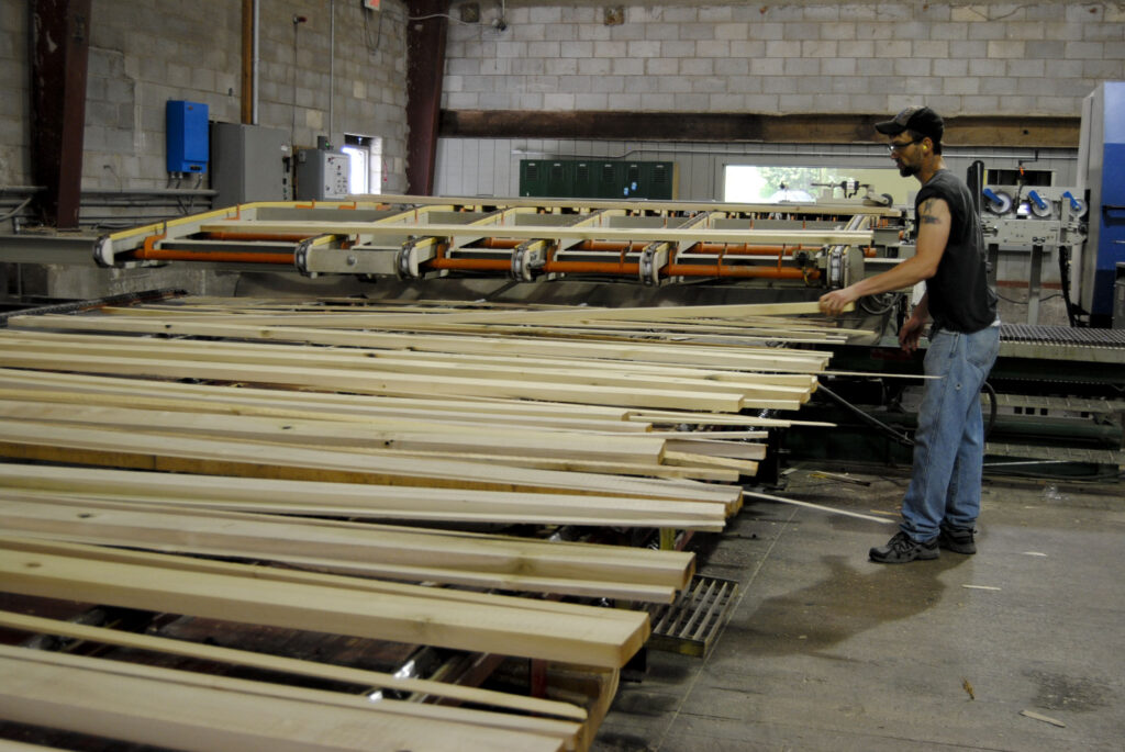 A man stands in front of several pieces of wood at powell Valley millwork.