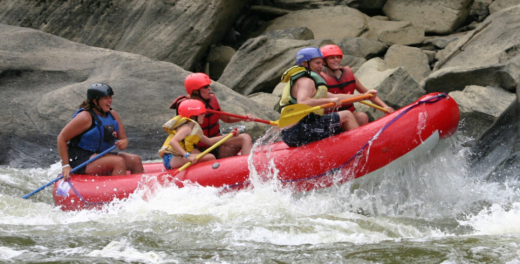 several people inside a raft going down the river at sheltowee trace adventure resort