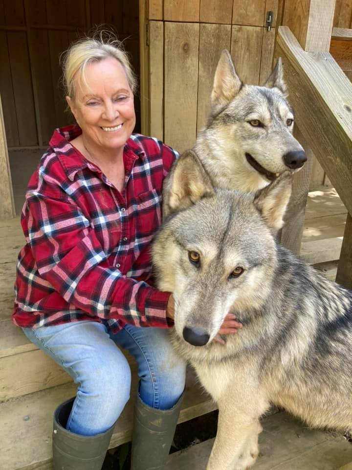 Marti Wilson smiles with two of the wolf dogs at Refuge Ridge in Whitley County, Kentucky