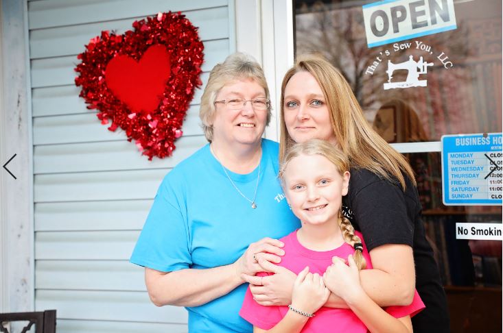 Susan Watson stands with her family in front of That’s Sew You quilt shop in Stanton, Kentucky. MACED provides them a business loan