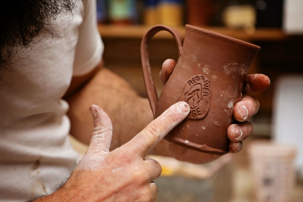 Person shapes a mug with a big foot outline on it as well as the words Red River Gorge.