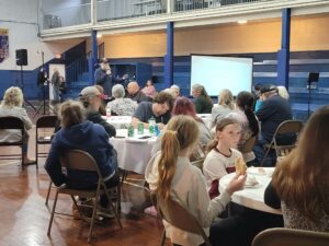 People sit at tables during the community listening session