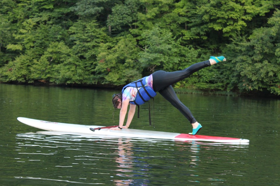 A person does yoga on a paddleboard on water at Carter Caves State Resort Park in Carter County Kentucky. 
