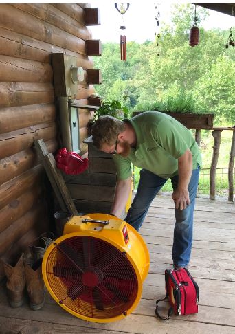 A new energy intern leans over to set up a blower door test at an energy efficiency audit for a business in Catlettsburg, Kentucky.